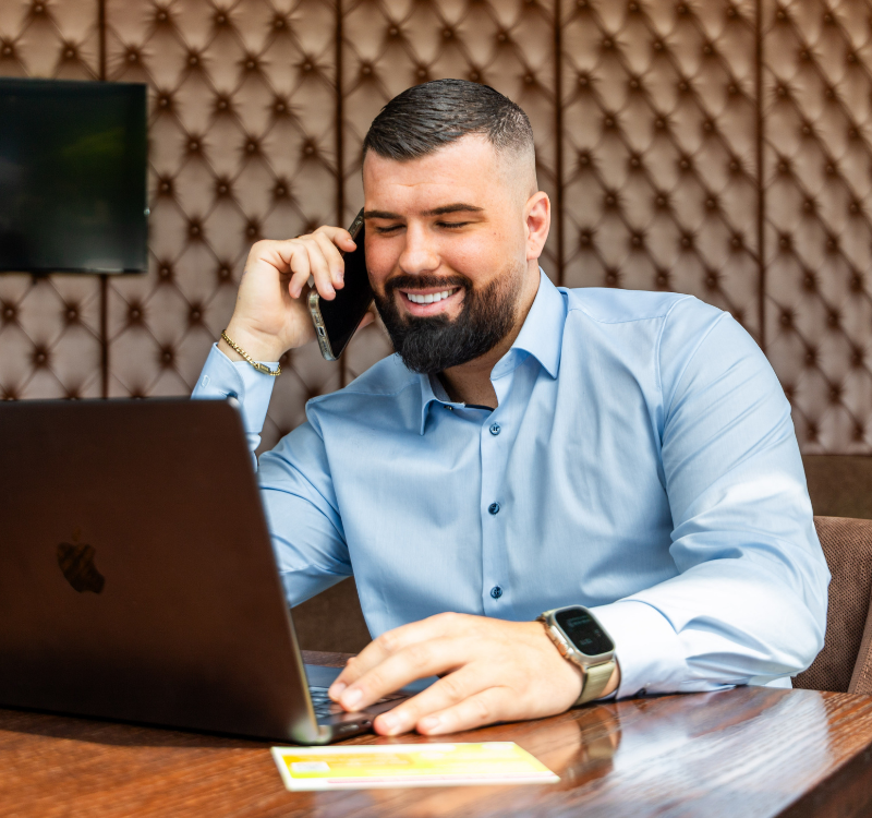 Zufriedener Geschäftsmann telefoniert und nutzt Laptop